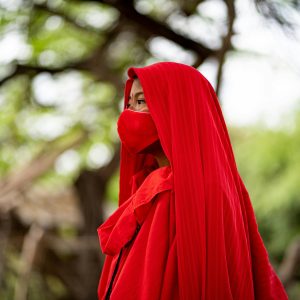 A person wearing traditional red clothing and mask in Guajira, Colombia. Vibrant and cultural setting.