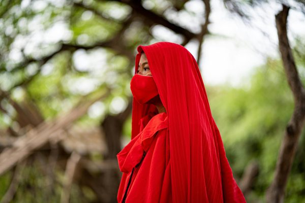 A person wearing traditional red clothing and mask in Guajira, Colombia. Vibrant and cultural setting.